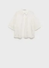Camisa blanca semitransparente con bordado de flores blancas, de manga corta y cuello camisero.