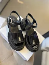 Sandalias negras de cuero charol con plataforma y correa al tobillo.