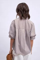 Camisa marrón a rayas verticales blancas y marrones, de corte amplio y mangas cortas.