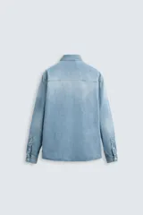 Camisa celeste de denim de algodón, corte relaxed fit, con cuello solapa, manga larga con puños abotonados, dos bolsillos de parche con solapa en el pecho, efecto lavado y cierre frontal abotonado.