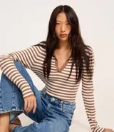 Blusa de punto con rayas horizontales marrones y blancas, cuello polo con escote en V y mangas largas.
