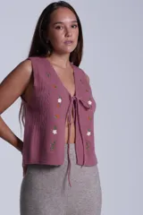 Chaleco tejido color crema con escote en V y cierre frontal con lazos. Presenta bordados de flores en tonos naranja, verde y blanco.