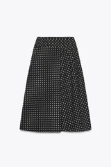 Falda midi negra con estampado de lunares blancos, de tiro alto y corte evasé.