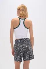 Top blanco de poliamida, corte cropped, al cuerpo y cuello a la base con ribete verde.