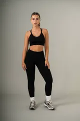 Conjunto deportivo negro, compuesto por un top con tiras cruzadas en la espalda y una calza de tiro alto con frunce en la parte trasera.