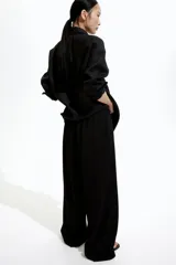 Pantalón negro de punto con cintura elástica y cordón ajustable. Corte holgado con piernas anchas y tiro alto.