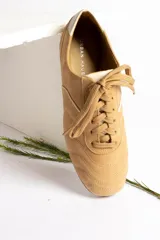 Zapatillas acordonadas color beige con detalles en blanco.