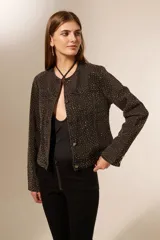 Campera de jean negra con tachas plateadas, corte clásico, cuello redondo y cierre con botones metálicos.