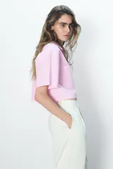 Camisa celeste de popelín con cuello solapa, escote pico y manga corta. Presenta dos bolsillos delanteros de parche y cierre frontal con botones.