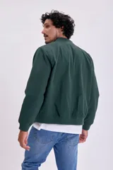Campera bomber verde con cierre frontal y cuello, puños y cintura acanalados.