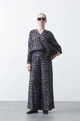 Pantalón de fit wide leg con estampado abstracto en tonos azul, marrón y beige. Presenta cintura elástica y caída fluida.