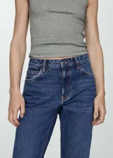 Pantalón de jean azul oscuro, tiro alto, corte mom fit, con cinco bolsillos y cierre de cremallera y botón.
