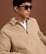 Campera masculina color marrón confeccionada en sarga, con cuello inglés, cierre de cremallera frontal, manga larga y bolsillos con detalles.