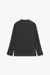 Camisa negra de lyocell con cuello redondo, manga larga con puños y bajo asimétrico con aberturas laterales. Cierre frontal con botones.