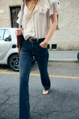 Pantalón de jean azul oscuro, de tiro bajo, corte slim fit y bootcut. Con cinco bolsillos y cierre frontal con cremallera y botón.