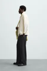 Sobrecamisa color crema de tejido técnico ligero, corte regular fit, cuello solapa, manga larga con puño abotonado, bajo ajustable con elástico en laterales y cierre frontal con cremallera.