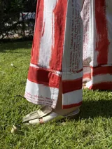 Pantalón de corte palazzo con estampado de rayas verticales rojas y texto ilegible sobre fondo blanco.