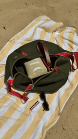 Bolso negro tipo tote de neopreno con bolsillo interno de red, sobre haciendo juego y gancho para sujetarlo.