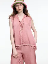 Camisa gris sin mangas confeccionada en viscosa teñida en frío, con efecto gastado. Tiene cuello clásico, cartera oculta y ruedo irregular más largo en los laterales.