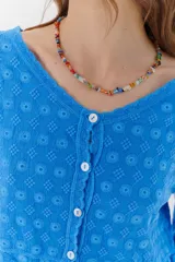 Camisa celeste de algodón con textura arrugada y bordados a tono, escote amplio, mangas largas y botones frontales.