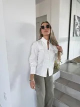 Camisa blanca de corte clásico con detalles de encaje en el frente y mangas largas con puños abotonados.