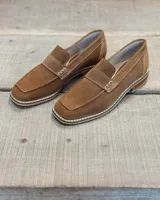 Mocasín de gamuza color marrón claro con detalle de hebilla y suela clara.
