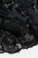 Camisa negra con textura, cuello clásico, abotonada al frente, canesú con pliegues en la espalda, mangas largas con puños abotonados y bajo redondeado.