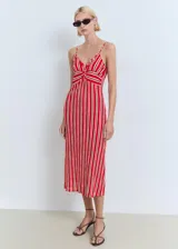 Vestido midi de tirantes finos ajustables, con escote de pico y detalle fruncido en la parte frontal del busto. Presenta un estampado de rayas verticales rojas y beige.