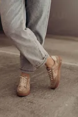 Zapatillas bajas color beige con estampado de piel de serpiente metalizada, cordones blancos y suela color caramelo.