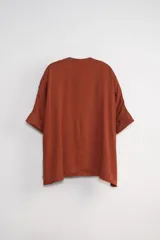 Blusa color terracota con escote en V y mangas cortas.