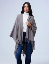 Ruana de tejido suave color negro con terminación en flecos, diseñada para un look cómodo y elegante.