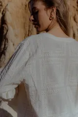 Camisa blanca de broderie con escote en V y mangas largas.