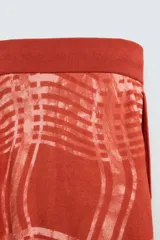 Pantalón relaxed fit de punto ligero tejido en hilatura de algodón color ladrillo con estampado a cuadros difuminados en blanco. Cintura elástica ajustable con cordón y bolsillos laterales.