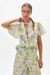 Camisa amarilla de lino con estampado floral en tonos azules, cuello mao y mangas cortas con volados. Cierre frontal con botones. Marca Francesca.