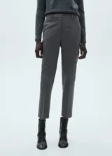 Pantalón gris de corte recto, tiro medio y diseño crop. Con cierre de cremallera y gancho, trabillas y bolsillos laterales.