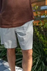 Bermuda de lino imperial a rayas verticales blancas y grises, con bolsillos laterales y traseros y elástico en la cintura.