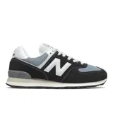 Championes New Balance modelo ML574HF2, color negro y gris claro, con logo 'N' blanco. Presentan una combinación de materiales como gamuza y malla, y entresuela con tecnología ENCAP.