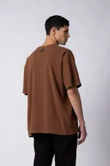 Remera de hombre color crudo, corte oversize, confeccionada en algodón grueso con textura micropanal. Diseño liso sin logos, con costura en forma de 'X' en la espalda. Ideal para un look casual y relajado.