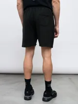 Bermuda deportiva negra de felpa con efecto lavado, con logo Umbro estampado en blanco en la pierna derecha.