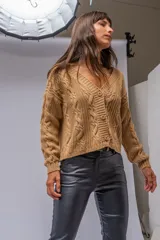 Saco color beige de tejido de punto trenzado, con escote en V y cierre frontal con botones marrones.
