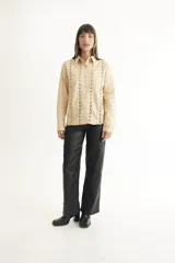 Pantalón de cuerina negro, de corte recto y tiro medio, con cinco bolsillos funcionales.