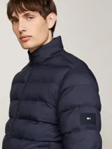 Campera acolchada azul con aislamiento térmico, cuello levantado y cierre de cremallera, decorada con un parche del logo de Tommy Hilfiger.