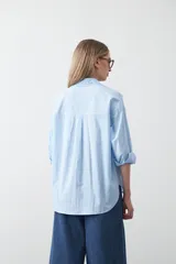 Camisa blanca de algodón con diseño utilitario y calce relajado. Presenta dos bolsillos frontales de estilo cargo con tapa y costuras a contratono.