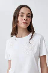 Remera blanca de algodón con cuello redondo y bordado de flores en el frente.