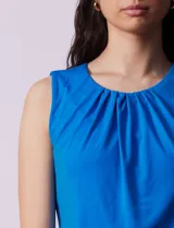 Blusa sin mangas color amarillo, con cuello redondo con frunces delanteros y abertura con botón en la espalda.