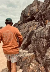 Buzo color ladrillo de corte estándar con estampa en la espalda de una ola, un sol y una palmera.