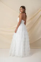 Vestido largo de fiesta color blanco, strapless, con corsé drapeado y falda amplia con volados de tul. Ideal para novias.