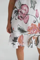 Vestido corto sin mangas, con estampado de flores rosas y naranjas sobre fondo blanco.