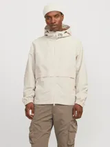 Campera shell ligera color beige, de manga larga con capucha y fit cómodo. Confeccionada en tejido plano fino de nylon, con cierre frontal de cremallera, bolsillos delanteros funcionales y puños de canalé.
