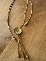 Collar con cordón regulable y dije dorado con textura irregular, inspirado en medusas.